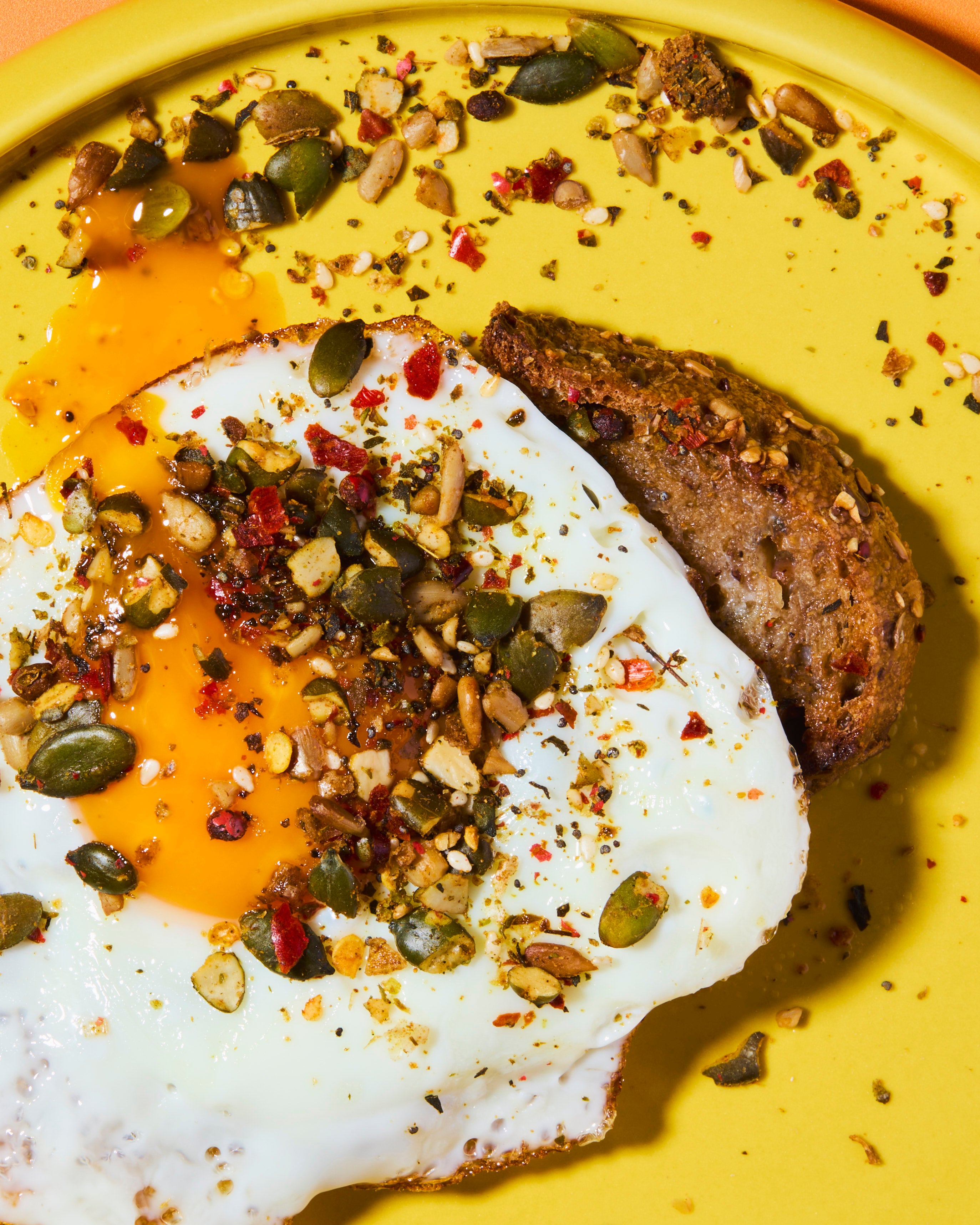 Fried egg with toast topped with punch your eggs spicy food topper on yellow plate