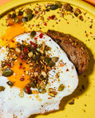 Fried egg with toast topped with punch your eggs spicy food topper on yellow plate