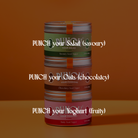 Three stacked metal cans of PUNCH food supplements on a warm brown background, with white text overlay reading 'PUNCH your Salad (savory)', 'PUNCH your Oats (chocolatey)', and 'PUNCH your Yoghurt (fruity)'.